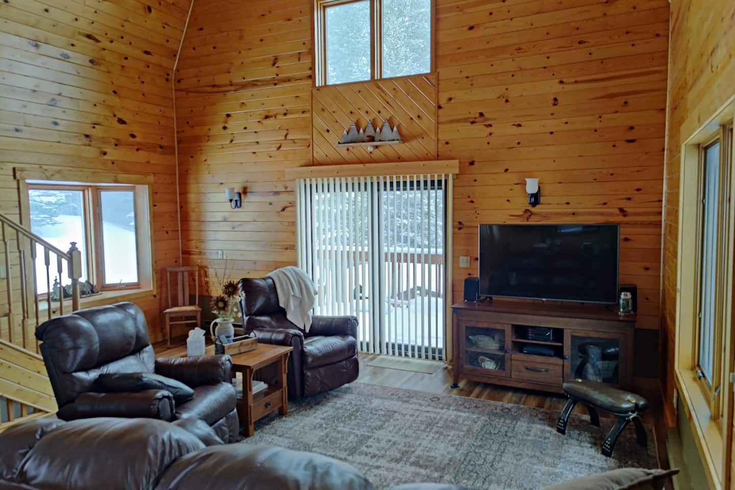 Pine-paneled living room with tall ceilings, comfortable couches and windows